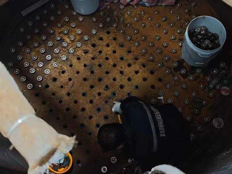 打开人孔后的钠离子交换器罐内：布水孔板与滤帽，施工人员在罐内作业