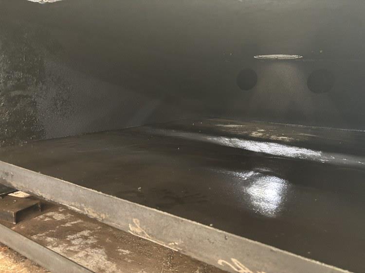 浮选槽内腔底部涂层涂敷进行中，可见涂层边界与未处理的钢板基面